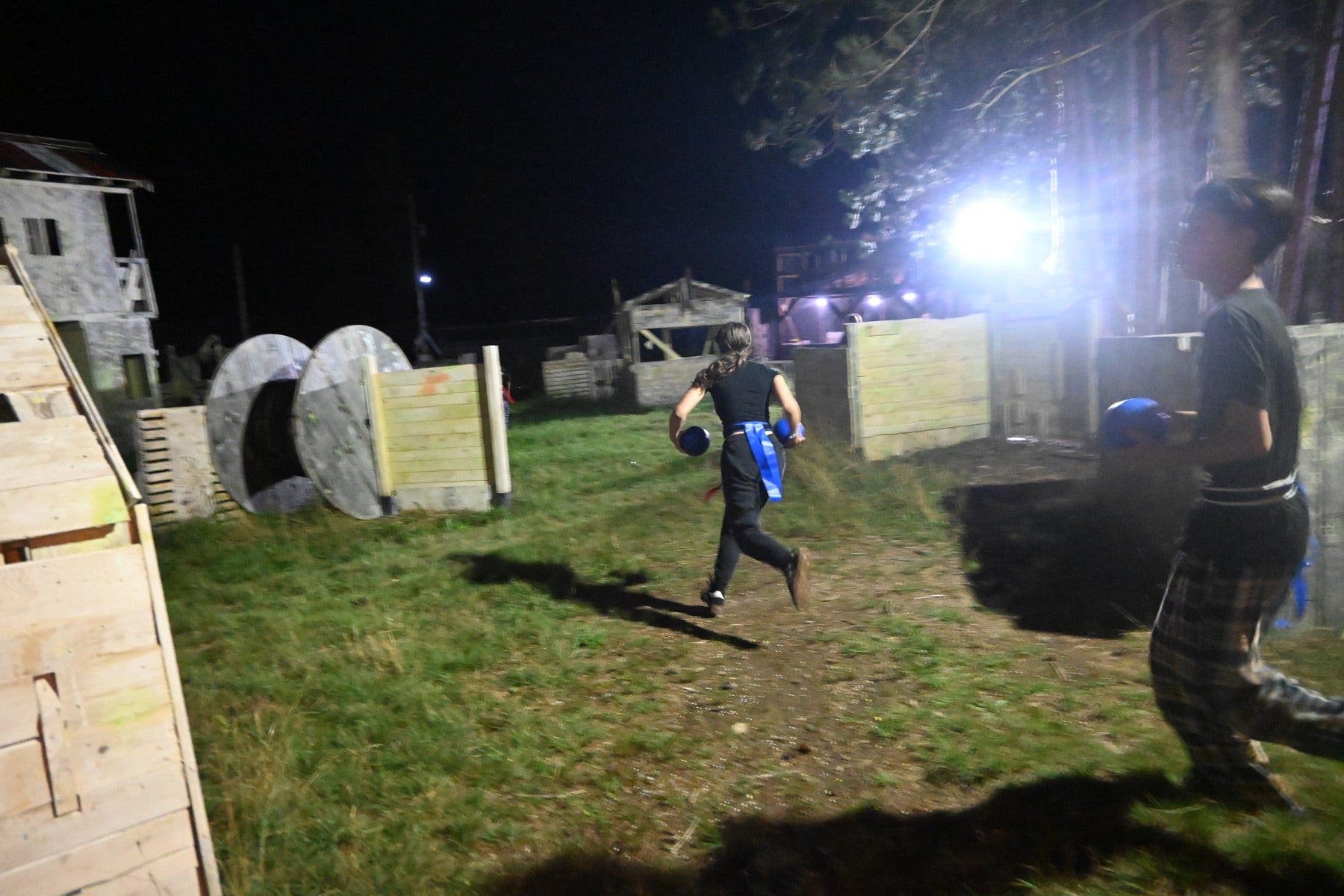 Players sprinting with blue team balls under the field lights